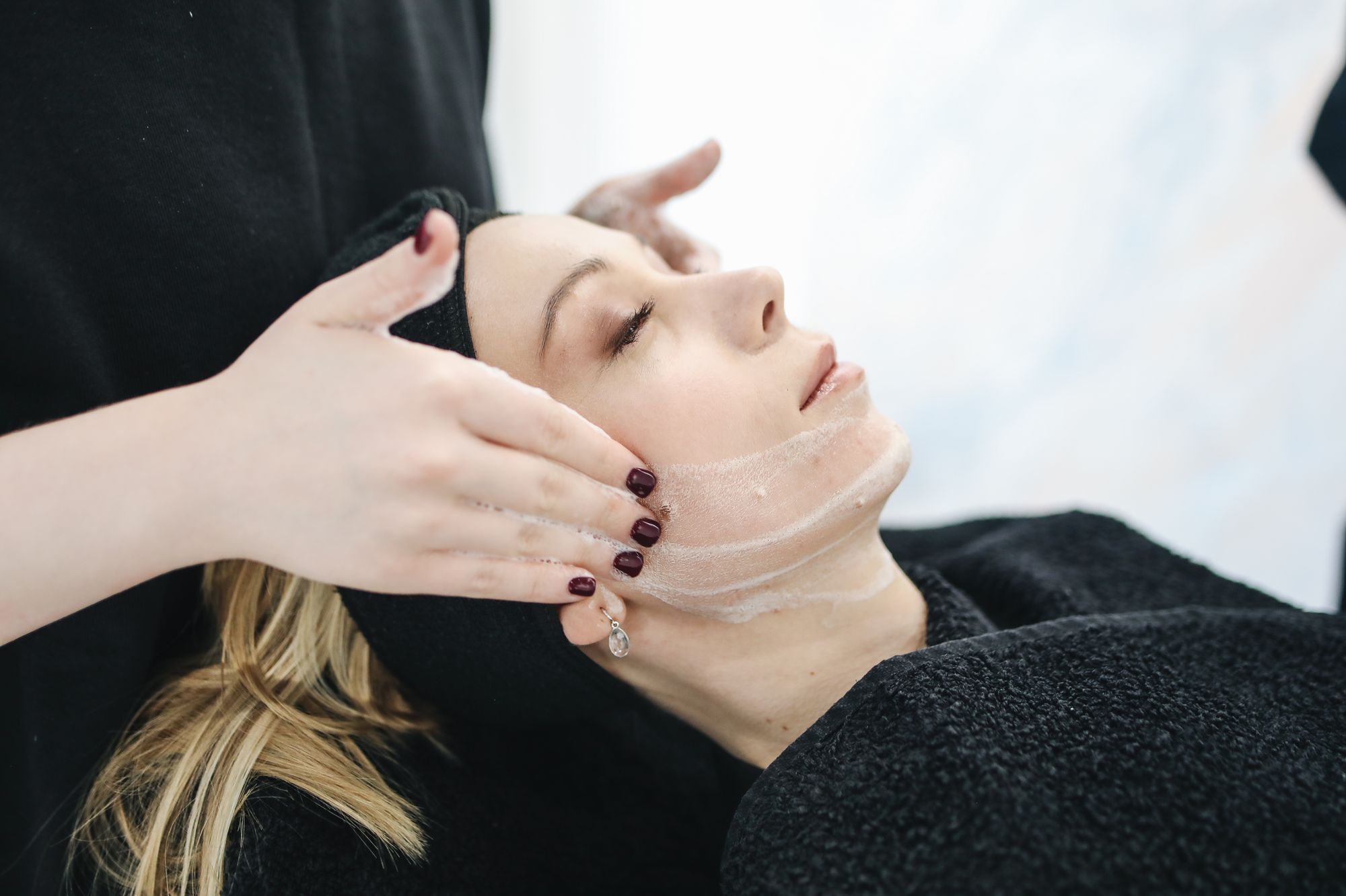 A practitioner's hands performing a careful treatment along a client's jawline.