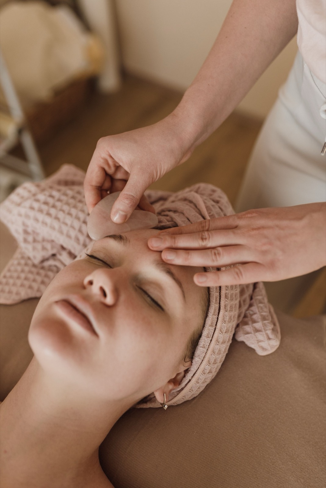 A client resting with eyes closed during a calm facial treatment at an aesthetic clinic.